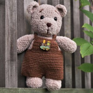 bear in crocheted brown overalls with a train pin